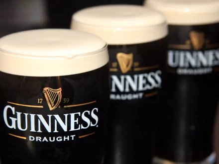 Three glasses of Guinness Draught beer, showcasing the iconic black design and creamy foam tops, serve as a striking HD wallpaper and background.