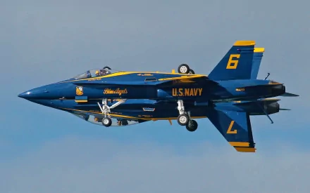 HD PC desktop wallpaper of a U.S. Navy Blue Angels aircraft vehicle (F/A-18) inverted with landing gear down, blue-and-gold livery against a pale sky.