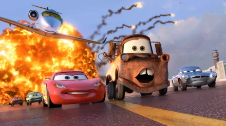 A vibrant scene from Pixar's Cars 2 featuring Lightning McQueen and Mater racing past an explosion, with an airplane in the background. HD wallpaper captures the movie's excitement.