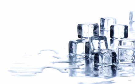 Clear ice cubes sit on a reflective surface, with melted water pooling around them. This HD photography serves as a striking desktop wallpaper and background.