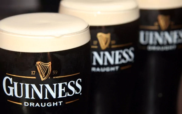 Three glasses of Guinness Draught beer, showcasing the iconic black design and creamy foam tops, serve as a striking HD wallpaper and background.