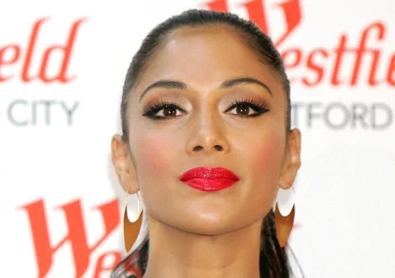 HD PC desktop wallpaper: close-up portrait of a music artist with sleek pulled-back hair, bold red lipstick and large hoop earrings against a white backdrop with blurred red text.