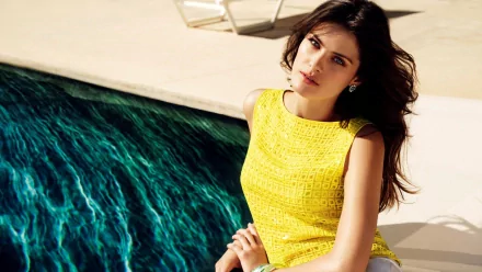 HD desktop wallpaper featuring celebrity Isabeli Fontana in a bright yellow dress, posing by a pool with vibrant blue water in the background.