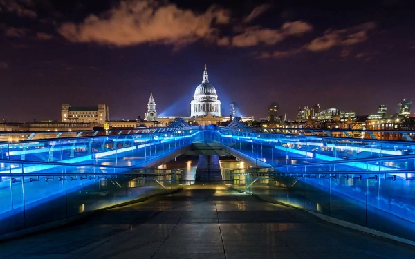 Night view of London's Millennium Bridge illuminated in blue, leading to St. Paul's Cathedral, captured as a high-definition desktop wallpaper background.