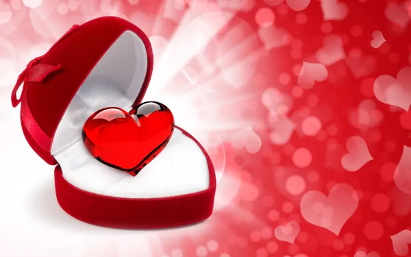 HD PC desktop wallpaper featuring a red glass heart inside a velvet heart-shaped box, set against a glowing red bokeh background for Valentine's Day.