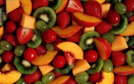 A vibrant arrangement of various fruits, including strawberries, kiwi, peaches, and grapes, creating a colorful and fresh backdrop for an HD desktop wallpaper.