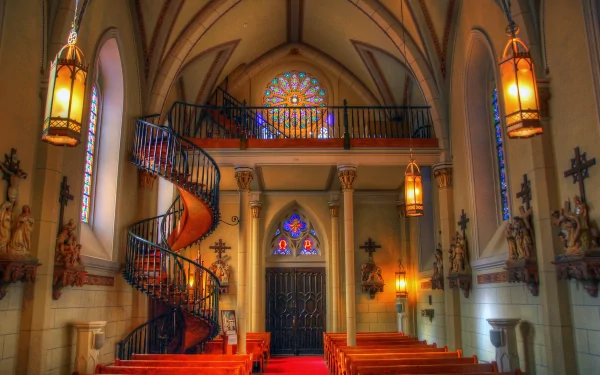 A stunning interior view of Loretto Chapel, showcasing its intricate architecture, spiral staircase, and vibrant stained glass windows. A serene setting for reflection and admiration.