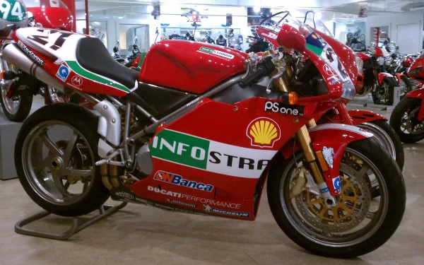 HD PC desktop wallpaper featuring a red Ducati race bike in a racing garage filled with motorcycles and racing gear.