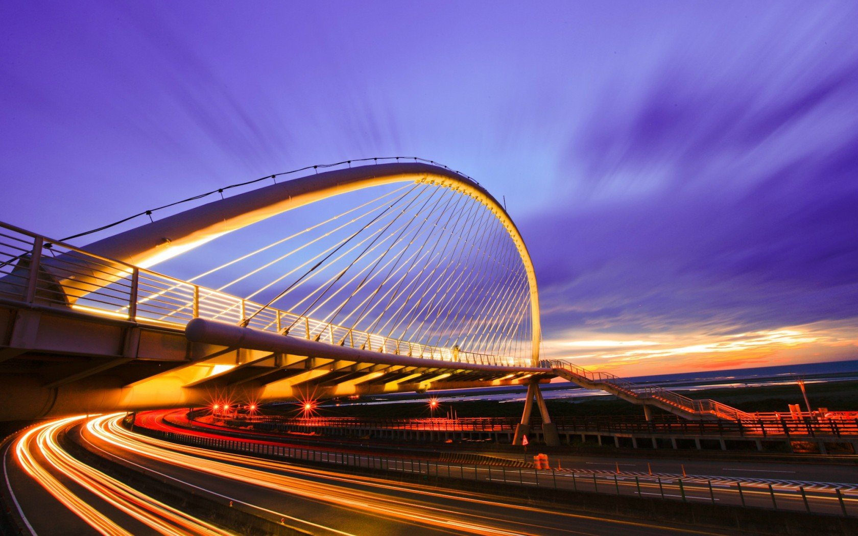 HD PC desktop wallpaper/background — time-lapse photography of a glowing arched bridge at dusk, streaking light trails and a vivid purple sky.