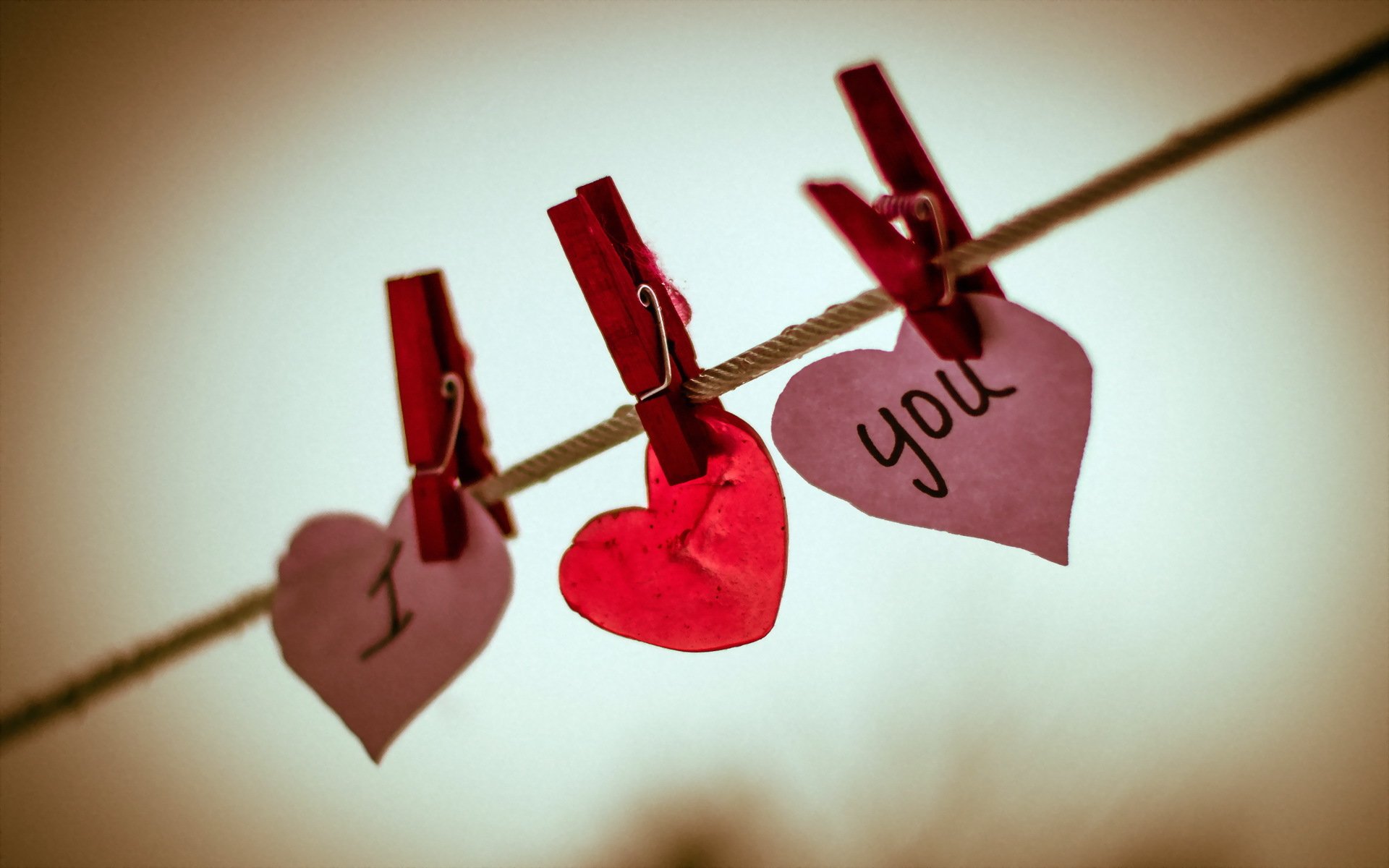 HD PC desktop wallpaper and background — three paper hearts clipped to a clothesline with clothespins; pink hearts read I and you flanking a red heart, holiday Valentine's Day theme.