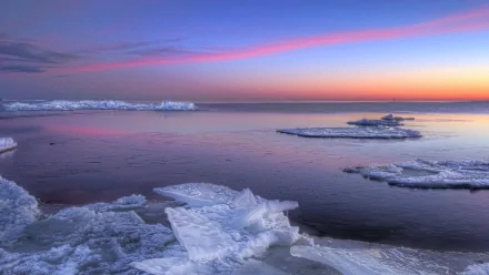 HD PC desktop wallpaper of nature and ice: icy shoreline and floating ice sheets on a calm sea beneath a pink‑purple sunset.