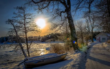 HD PC desktop wallpaper featuring a serene snowy landscape with a boat resting by the frozen shore under a bright sun and clear blue sky.
