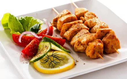 A vibrant plate of grilled barbecue skewers paired with fresh salad, garnished with lemon and herbs, creates an appetizing HD desktop wallpaper.