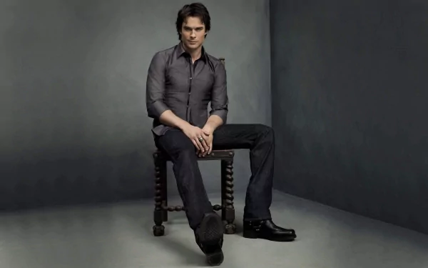 HD desktop wallpaper of celebrity Ian Somerhalder, showcasing him seated on a stool against a minimalist, dark background.