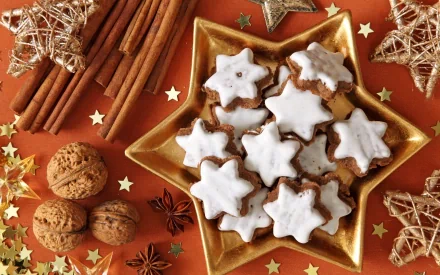 HD PC desktop wallpaper featuring star-shaped iced cookies on a golden star plate, surrounded by cinnamon sticks, walnuts, anise, and decorative stars.