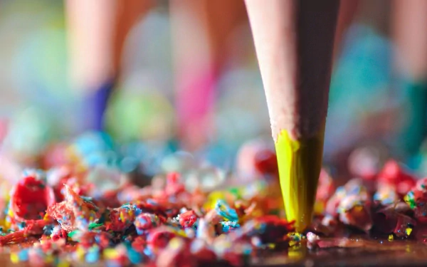 Close-up photography of a sharpened pencil tip touching colorful shavings on a surface, presented as an HD PC desktop wallpaper and background.
