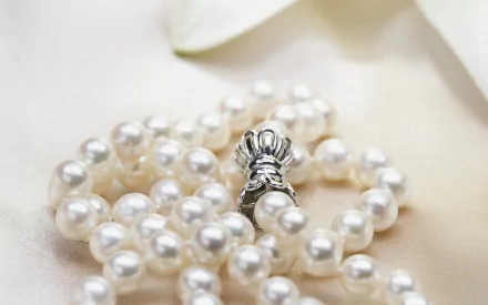 Close-up of a man-made pearl necklace with a silver clasp, captured in high definition for a PC desktop wallpaper background.