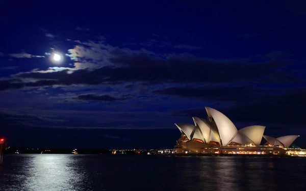 HD desktop wallpaper showcasing the Sydney Opera House illuminated at night under a bright full moon with city lights reflecting on the water.