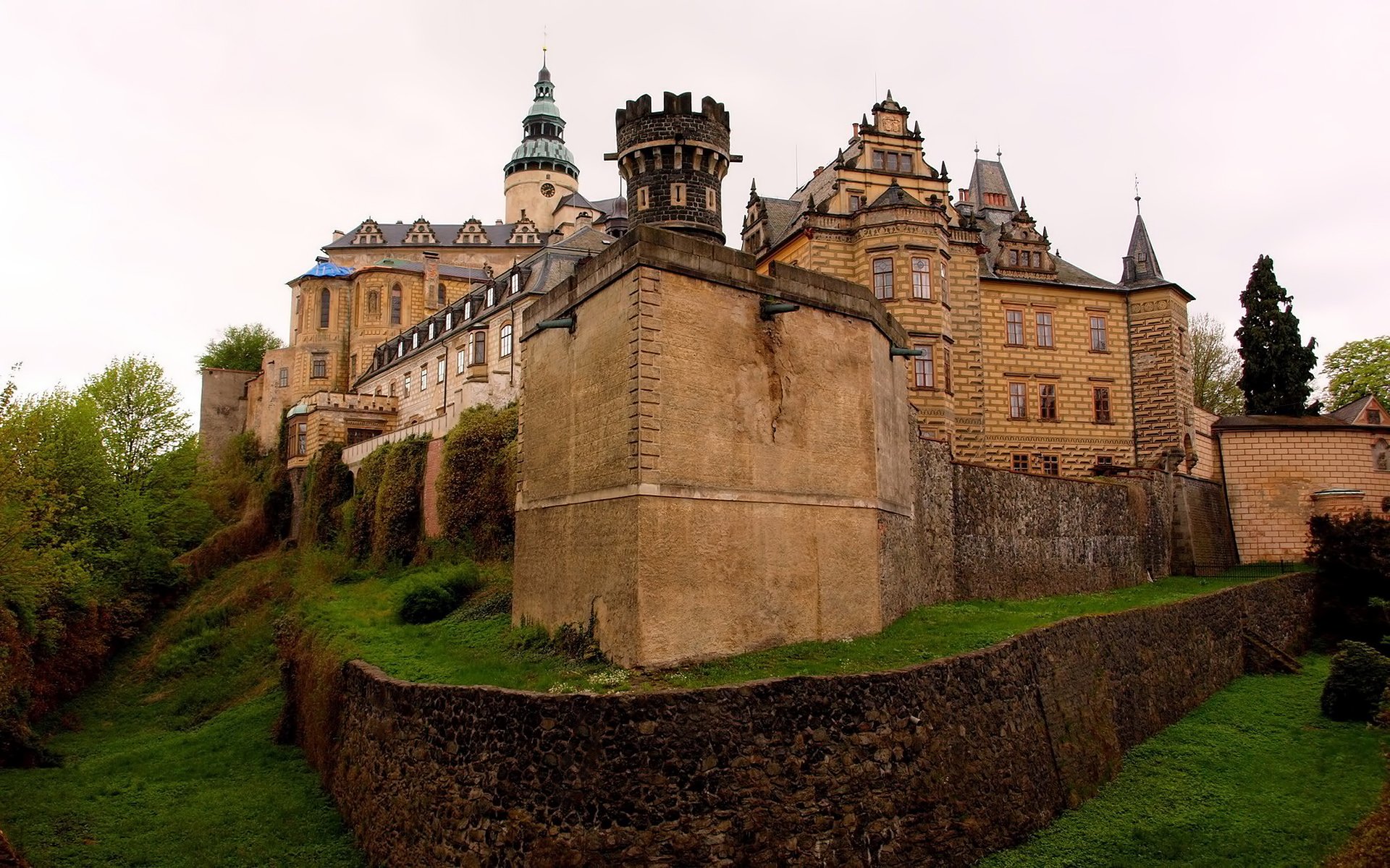HD desktop wallpaper featuring the historic man-made Frydlant Castle with its towering stone walls and intricate architectural details surrounded by greenery.