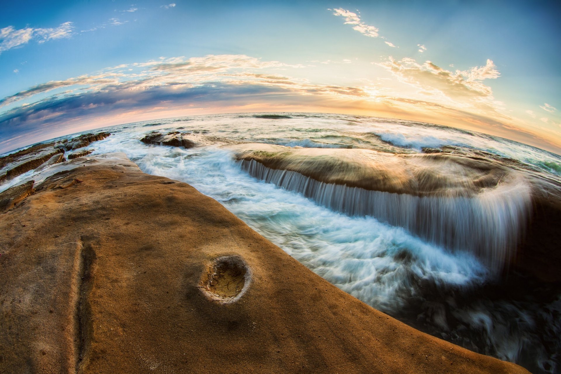 Nature, ocean 2K Quad HD PC desktop wallpaper: fisheye view of rocky shore with waves spilling into tide pools beneath a glowing sunrise sky.