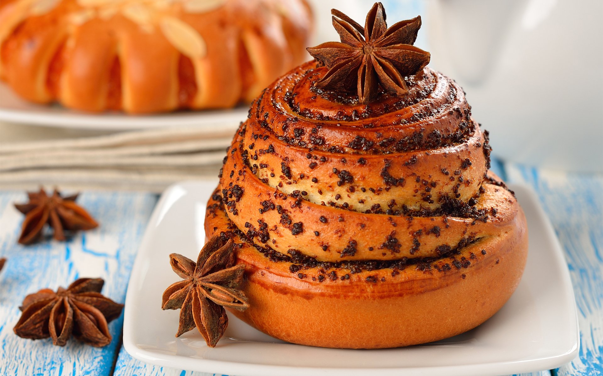 Close-up of a spiced cinnamon roll with star anise on a white plate, captured in HD for a PC desktop wallpaper featuring food and baking themes.