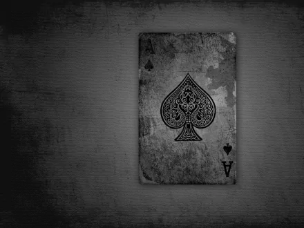 A high-definition desktop wallpaper featuring a weathered playing card with an intricate spade design against a textured gray background.