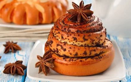 Close-up of a spiced cinnamon roll with star anise on a white plate, captured in HD for a PC desktop wallpaper featuring food and baking themes.