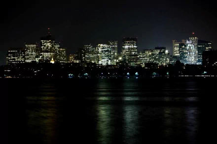 A stunning nighttime view of Boston’s skyline, showcasing illuminated skyscrapers reflecting on the water. This 4K Ultra HD image captures the vibrant cityscape beautifully.