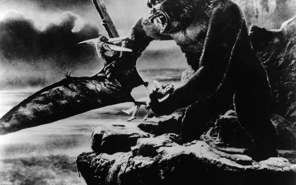 A dramatic black-and-white scene from the 1933 movie King Kong, featuring the iconic giant ape clashing with a massive pterosaur on a rocky ledge against a stormy backdrop.