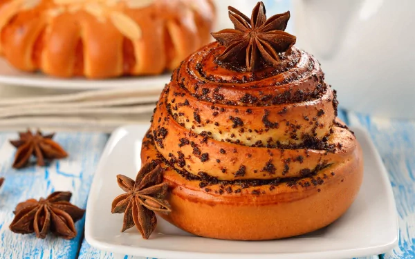 Close-up of a spiced cinnamon roll with star anise on a white plate, captured in HD for a PC desktop wallpaper featuring food and baking themes.