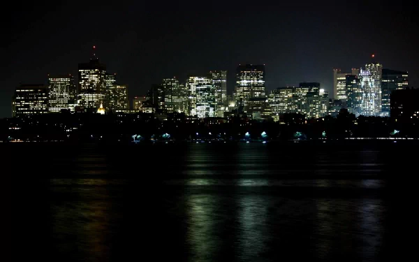 A stunning nighttime view of Boston’s skyline, showcasing illuminated skyscrapers reflecting on the water. This 4K Ultra HD image captures the vibrant cityscape beautifully.