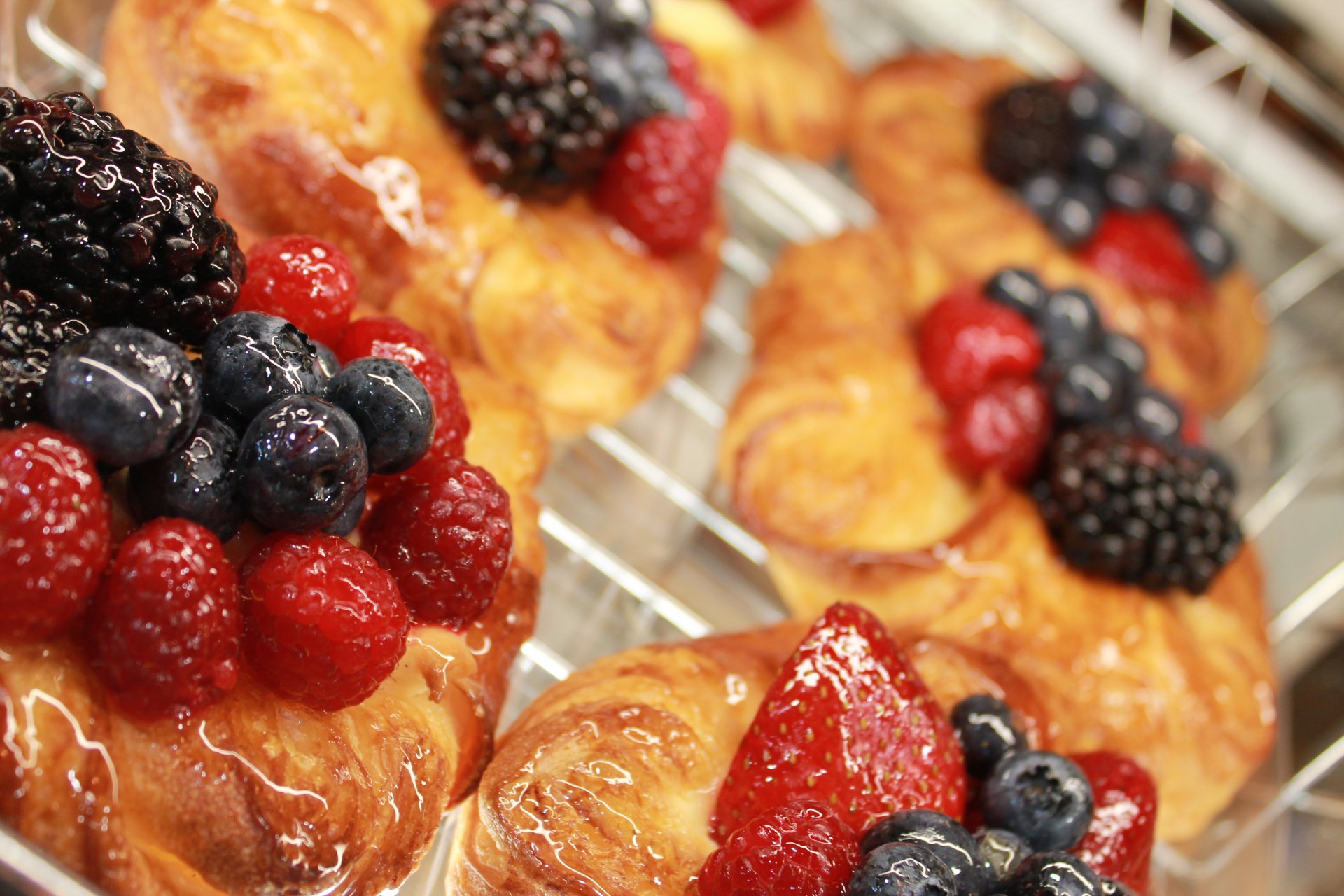 Close-up of freshly baked pastries topped with an assortment of berries, captured in vibrant 4K Ultra HD for a PC desktop wallpaper.