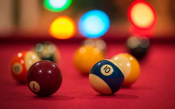 A close-up of colorful pool balls on a bright red table, illuminated by vibrant lights, creating an engaging desktop wallpaper for pool game enthusiasts.