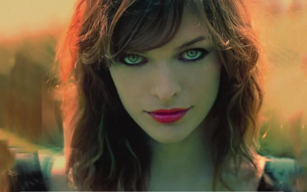 HD desktop wallpaper featuring celebrity Milla Jovovich with intense eyes and vibrant lipstick, set against a soft, blurred background.