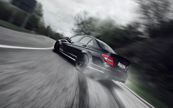 HD PC desktop wallpaper featuring a sleek black Mercedes-Benz C63 speeding on a winding road, surrounded by blurred trees and motion effects.