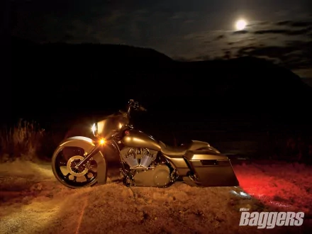 Gold 2007 Harley-Davidson Chopped Street Glide motorcycle parked on dirt under a moonlit sky, headlights aglow — HD desktop wallpaper.