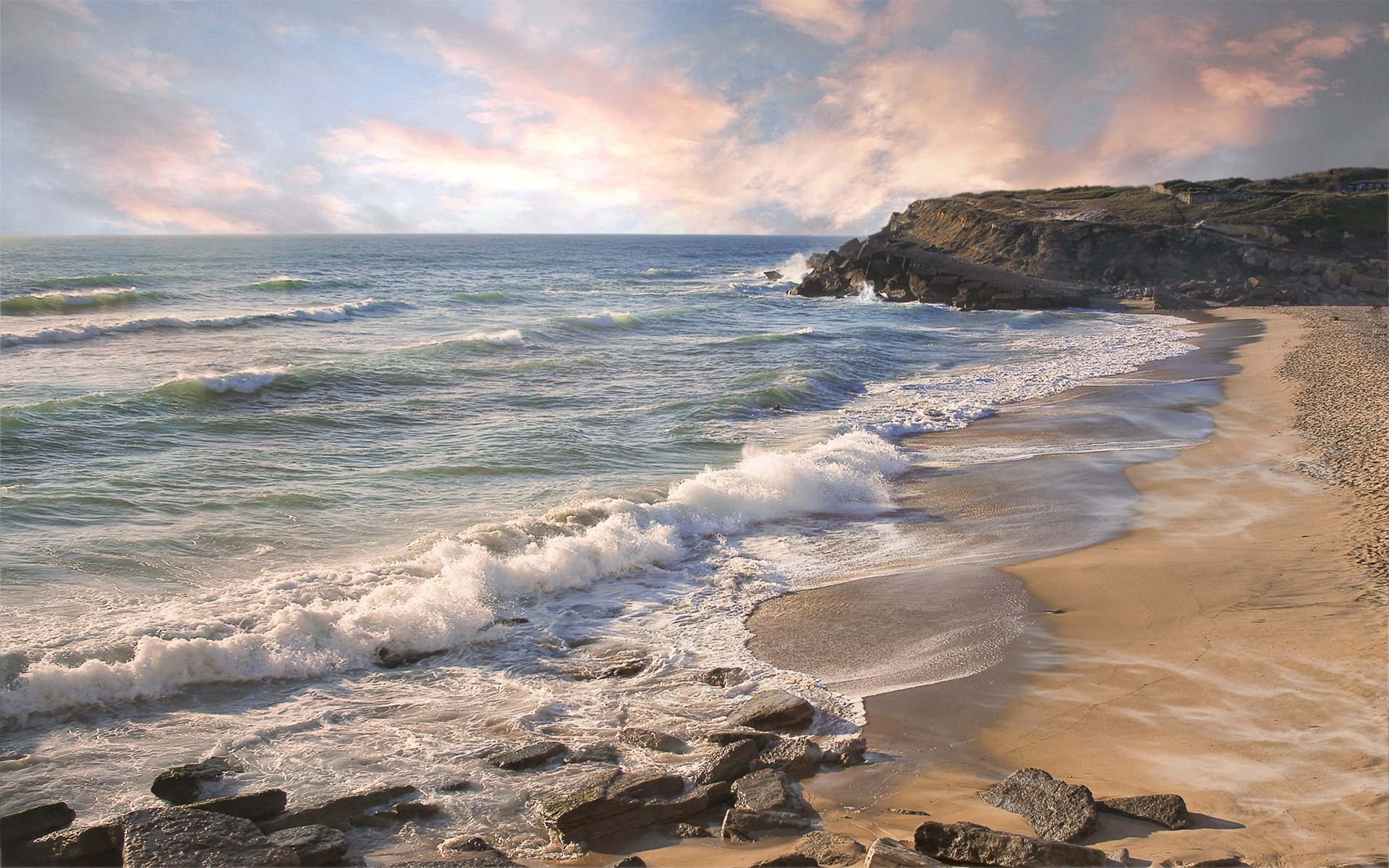 A serene beach scene featuring gentle waves lapping at the sandy coastline, with dramatic cliffs in the background under a beautiful sky. A captivating nature wallpaper.