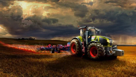 A Claas Axion 990 tractor works in a golden field under dramatic clouds, highlighting its robust design and powerful performance against a scenic rural backdrop.