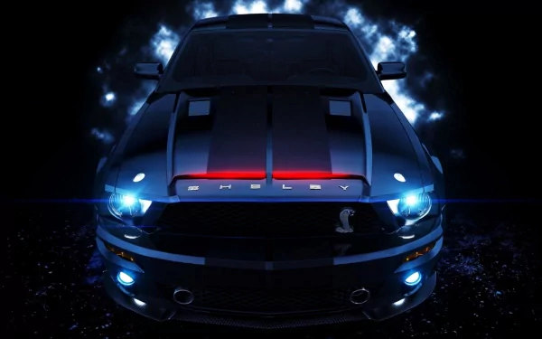 HD desktop wallpaper of a Ford Mustang Shelby GT500 with glowing blue headlights and a powerful front view, set against a dramatic, illuminated background.