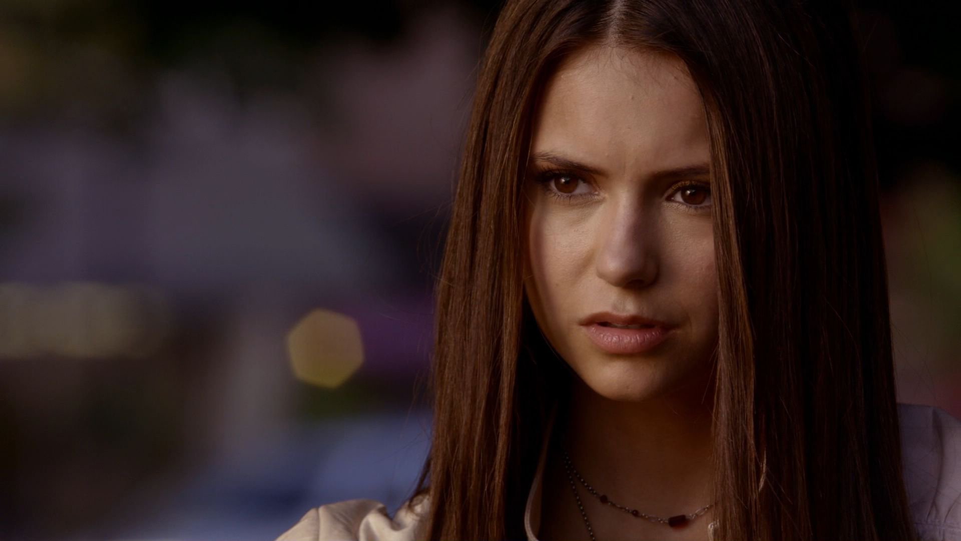 HD desktop wallpaper featuring celebrity Nina Dobrev with a serious expression, set against a softly blurred background.