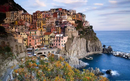 Colorful man-made village buildings perched on cliffs overlooking the sea in Manarola, Cinque Terre, Italy, captured in a vibrant HD desktop wallpaper.