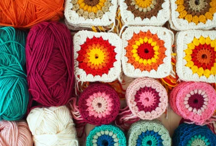 HD photography PC desktop wallpaper/background of colorful yarn skeins and crocheted granny squares, showcasing vivid colors and tactile textile texture.