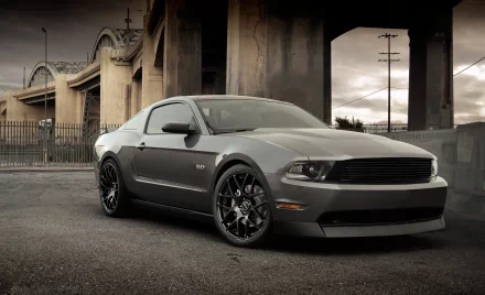 HD PC desktop wallpaper featuring a sleek gray Ford Mustang parked under an urban bridge with dramatic lighting and a moody sky.