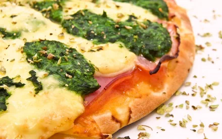 Close-up of a pizza with melted cheese, spinach, and herbs on a crust, captured in high definition for a vibrant PC desktop wallpaper background.