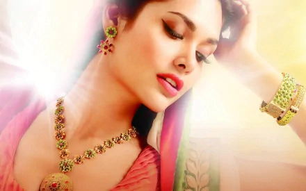 Esha Gupta gazes elegantly, adorned in intricate jewelry, featuring a vibrant background. This HD desktop wallpaper captures her beauty and cultural essence.