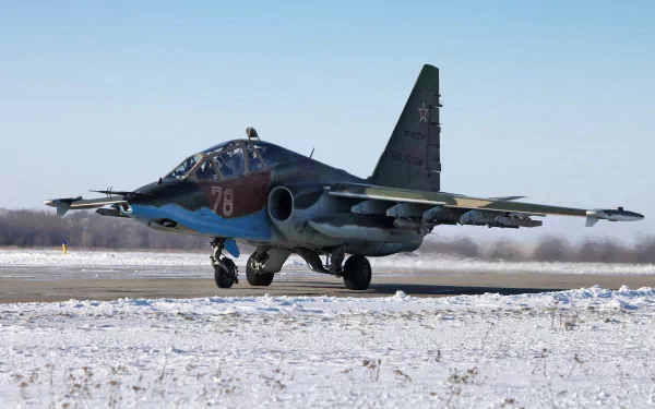 A Sukhoi Su-25 military aircraft taxiing on a snow-covered runway, showcasing its distinct camouflage and design in a high-definition desktop wallpaper.