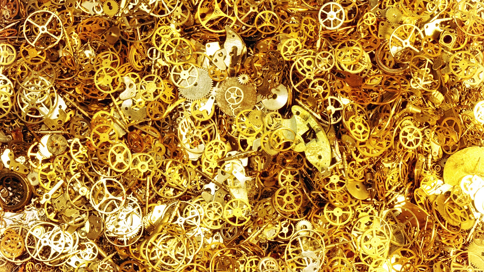 HD desktop wallpaper featuring a close-up view of numerous golden watch gears and components, showcasing intricate man-made mechanical details.