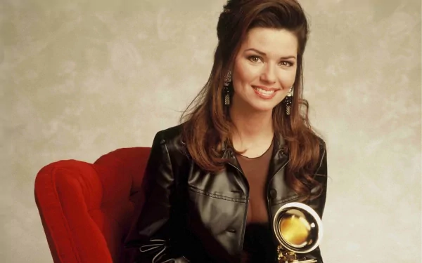 HD PC Desktop Wallpaper featuring Shania Twain smiling in a black leather jacket, holding a music award, against a neutral background.
