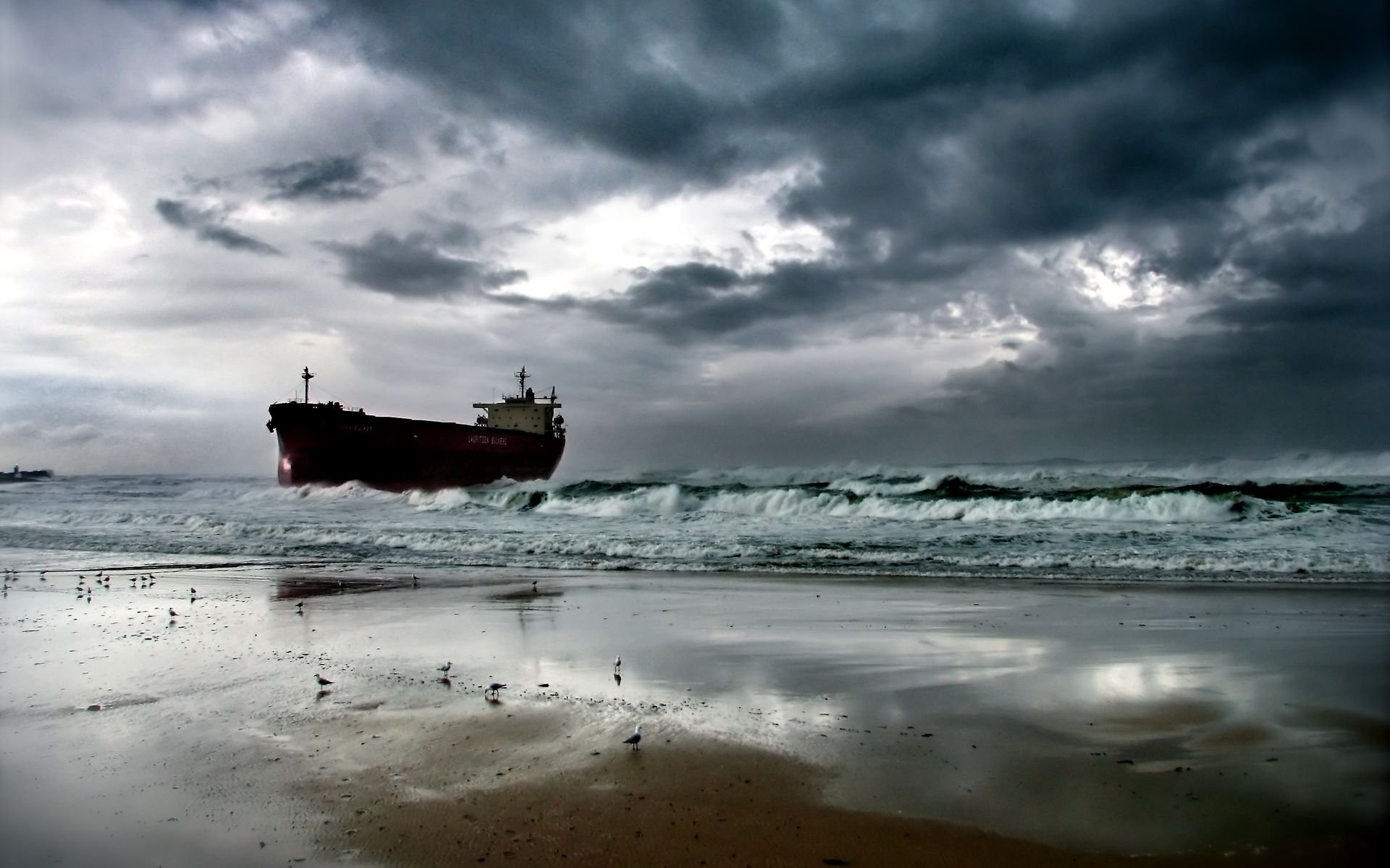 A dramatic view of a tanker vessel navigating rough seas under ominous clouds, captured in high definition as a stunning desktop wallpaper and background.