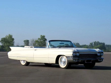HD desktop wallpaper featuring a classic white 1960 Cadillac convertible parked on an open road under a clear blue sky.